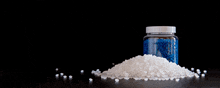 a jar of blue granules sits on a pile of white granules