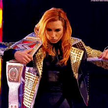 a woman in a studded jacket is holding a world heavyweight wrestling championship belt .