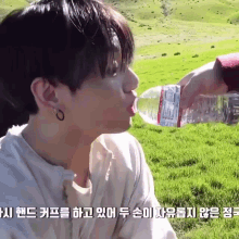 a young man drinking water from a bottle with a label that says ' water ' on it
