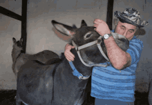 a man wearing a watch is hugging a donkey in a stable
