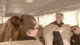 a woman wearing glasses sits on a bus with a man wearing sunglasses