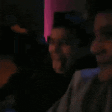 a group of people are sitting in a dark room with purple lights behind them .