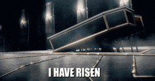 a coffin is laying on the ground in a dark room with the words `` i have risen '' written on the bottom .