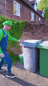 a man dressed as mario pushes a recycling bin