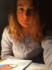 a woman sitting at a table with a book and a bracelet