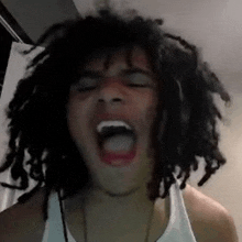 a man with dreadlocks is screaming with his mouth wide open .