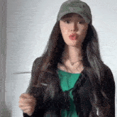 a woman wearing a hat and a green shirt is making a face .
