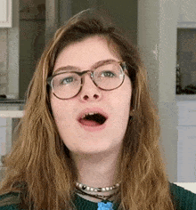 a young woman wearing glasses is making a funny face with her mouth open .