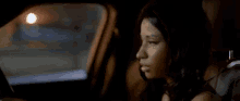 a woman is sitting in the back seat of a car with her eyes closed at night .