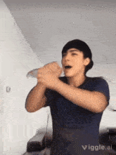 a young man in a blue shirt is making a funny face while holding something