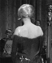 a woman in a dress is standing in front of a sign that says sss on it .