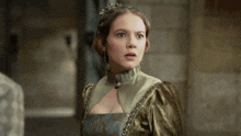 a woman in a green dress with a crown on her head looks surprised .