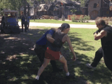 a man in a blue shirt is carrying another man in red shorts