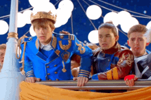 a boy in a blue uniform with a gold crown on his head