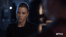 a woman in a dark room with a netflix logo in the background