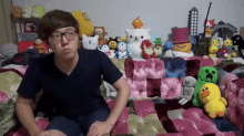 a man is sitting on a couch surrounded by stuffed animals and toys .