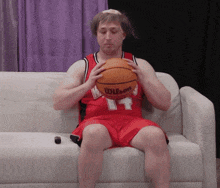 a man wearing a red wilson jersey holds a basketball