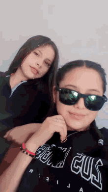 two girls are posing for a picture and one has a shirt that says ' guil gus ' on it
