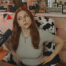 a woman sitting in front of a microphone with a cow print chair in the background