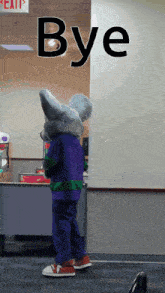 a child in a chuck e cheese mascot costume stands in front of a bye sign