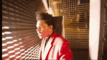a man in a red suit is standing in a hallway .