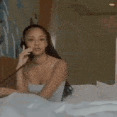 a woman is laying in bed talking on a phone .