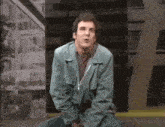 a man in a blue jacket is sitting on the ground