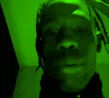 a man with dreadlocks is taking a selfie in a green light .