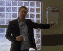 a man in a suit is standing in front of a glass block wall