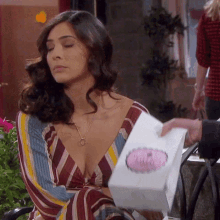 a woman in a striped dress is holding a box with a pink sticker that says ' i love you '