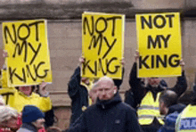 a group of people holding up yellow signs that say " not my king "