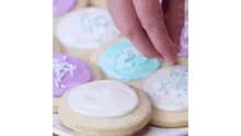 a person is decorating cookies with icing and sprinkles on a plate .