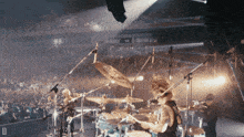 a man playing drums in front of a crowd with the letter d in the lower right corner