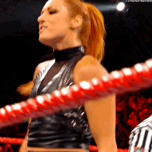 a woman in a black top is standing in a ring with a referee