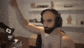 a shirtless man with a beard is wearing headphones and dancing in a room .