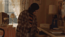 a woman in a plaid robe is opening a drawer in a room with #mrsmaiset written on the bottom