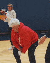 a woman wearing a red nike sweatshirt stands in front of a basketball net