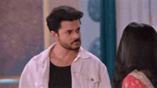 a man with a beard is looking at a woman in a red dress .