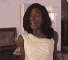 a woman in a white dress is smiling while standing in a room .