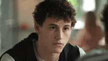a young man with curly hair is looking at someone