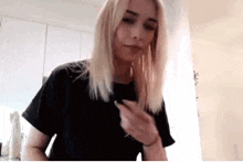 a woman with blonde hair is wearing a black t-shirt and holding a pen .