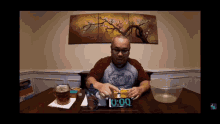 a man sits at a table with a clock that reads 0:00