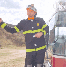 a man in a fireman 's uniform is standing in front of a blippi truck