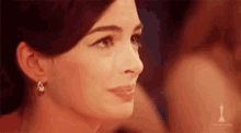 a close up of a woman 's face wearing earrings and looking at the camera .