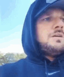 a man with a beard is wearing a nike hat and hoodie