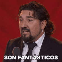 a man in a suit and tie is speaking into a microphone and the words son fantasticos are below him