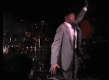 a man in a suit and pink shirt is playing a guitar on stage