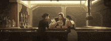 a group of people are sitting at a bar talking .