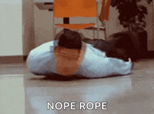 a man is laying on the floor with his head on a pillow and the words nope rope written above him .