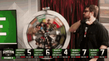 a man stands in front of a roulette wheel with the number 5 on it